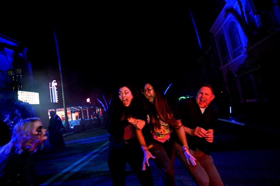 a group of people are walking down a street at night