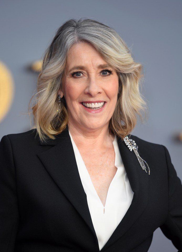 a woman wearing a black jacket and white shirt smiles for the camera