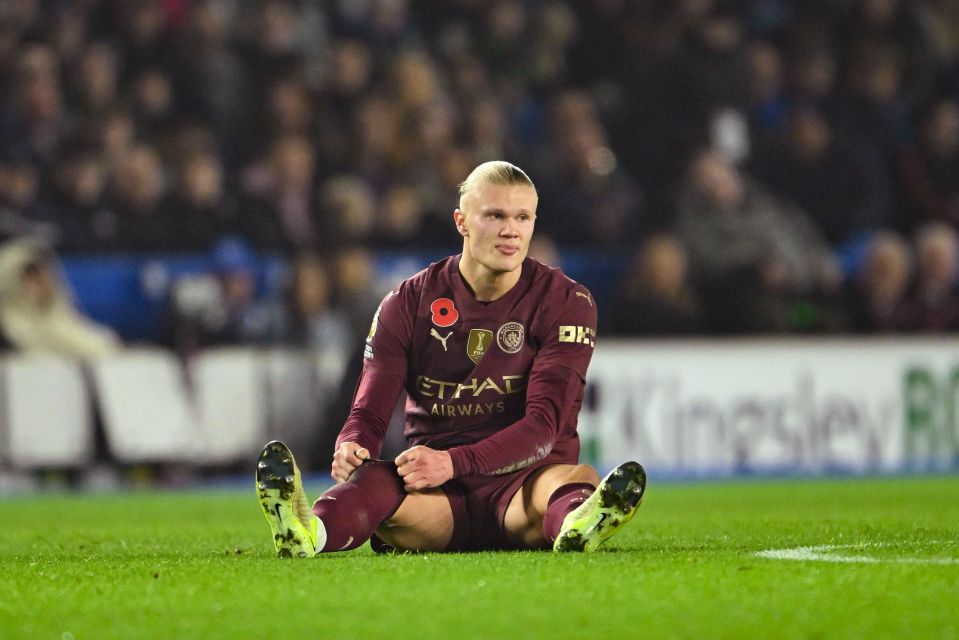 a soccer player sits on the field wearing an etihad airways jersey