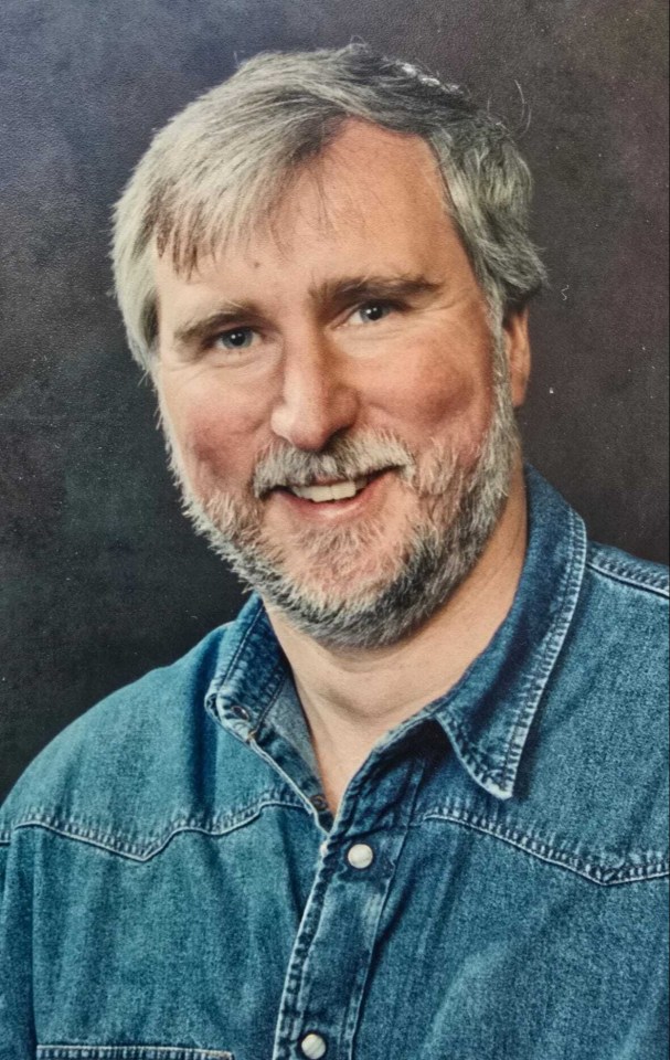 a man with a beard wearing a blue denim shirt