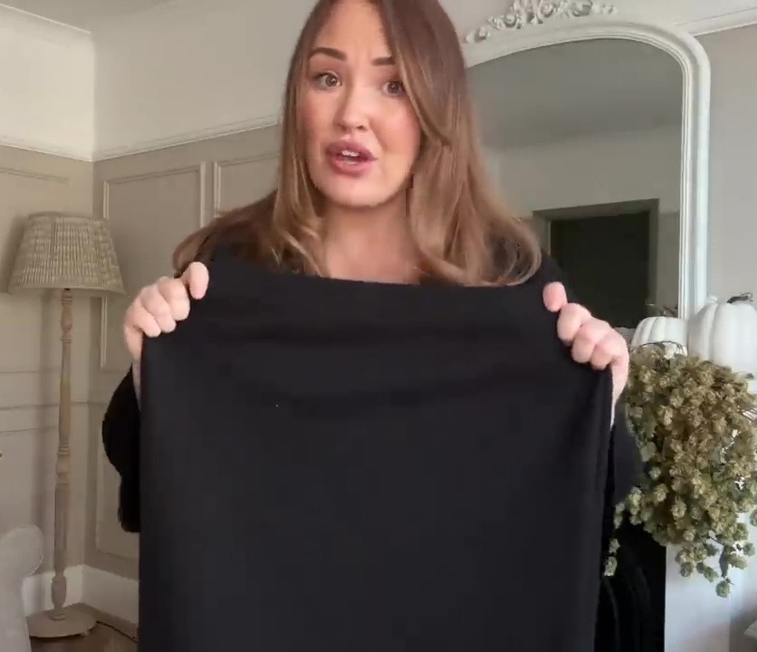 a woman is holding a black shirt in a living room