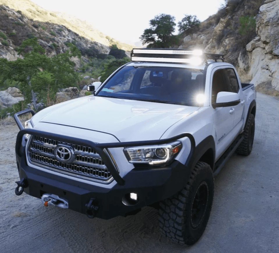 a white toyota tacoma is parked on a dirt road