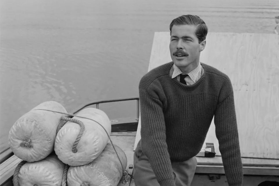 a man in a grey sweater is standing on a boat