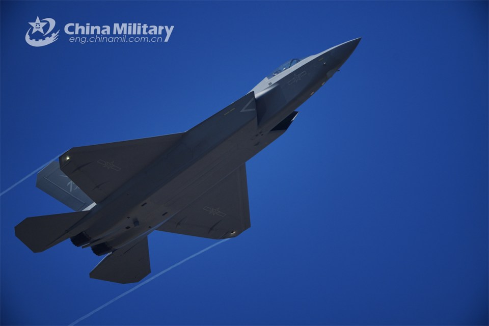 a fighter jet is flying through a blue sky with a china military logo behind it