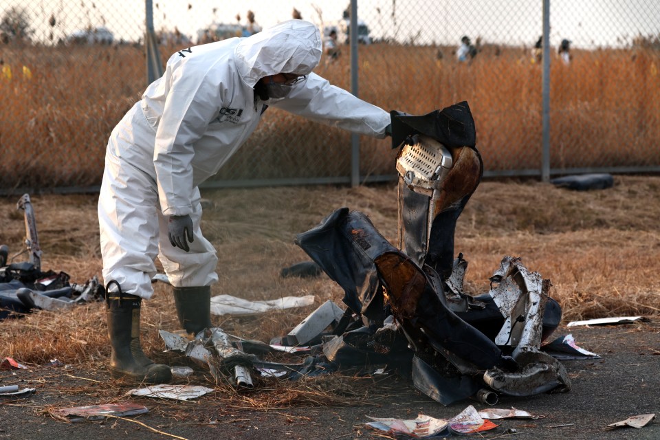 A crime scene investigator examines wreckage from a plane crash.