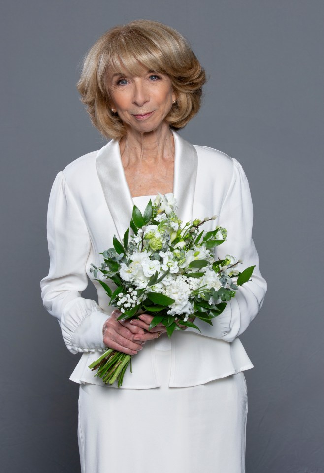 Gail Rodwell in a white wedding outfit, holding a bouquet.