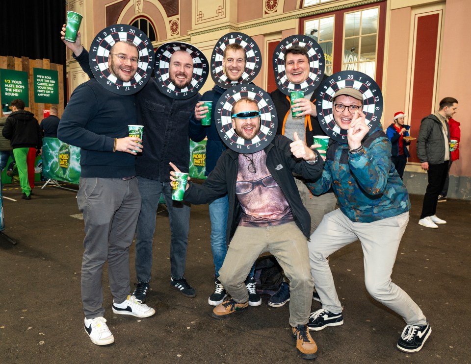 Group of men at a darts event wearing dartboards as hats.