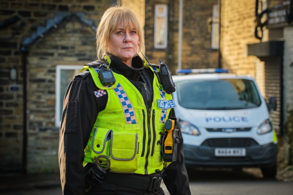 Catherine Cawood, a police officer from Happy Valley, stands in front of a police van.