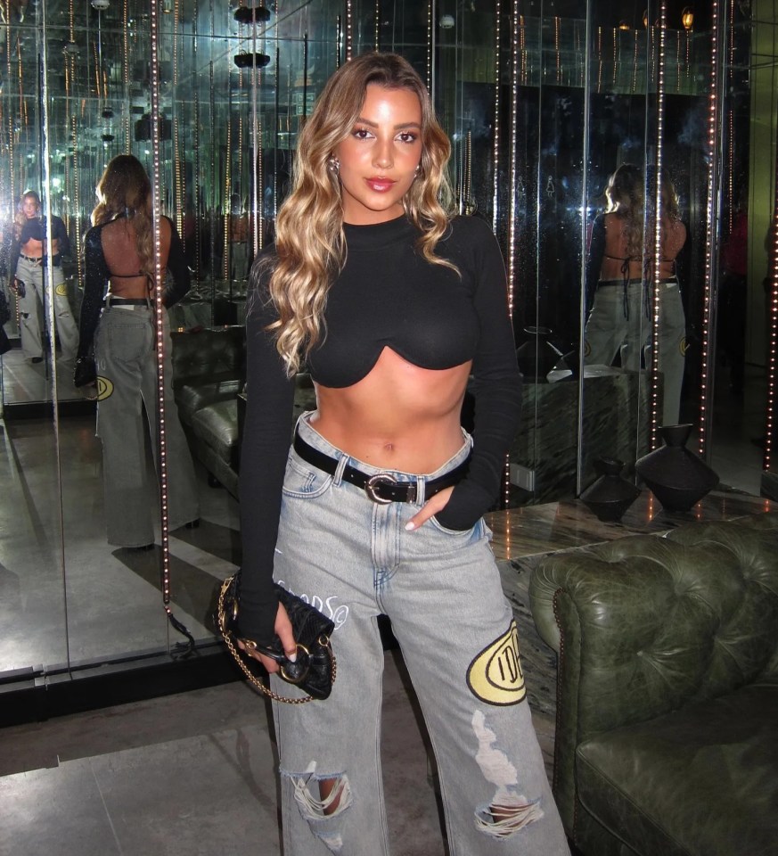 April Ivy in a black crop top and distressed jeans.