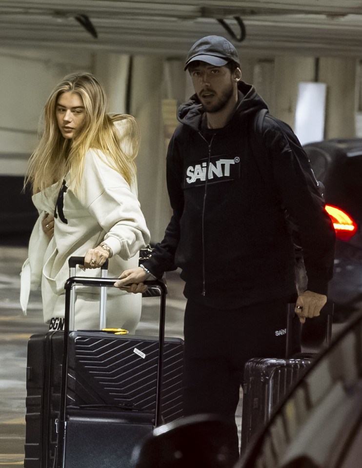 Rúben Dias and Arabella Chi at an airport, pulling luggage.
