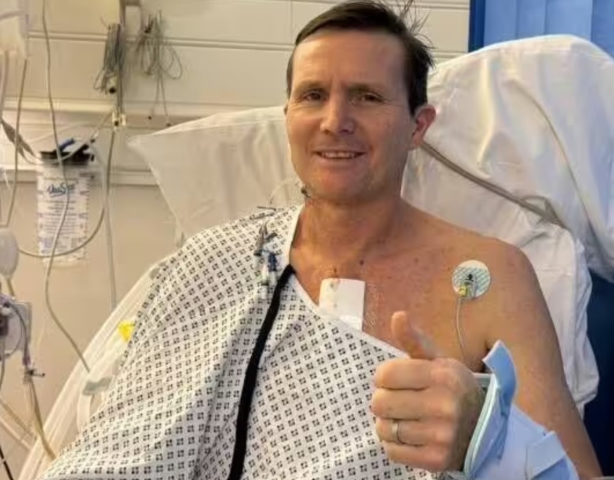 Man in hospital gown giving thumbs up.