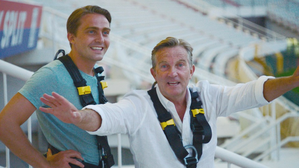 Bradley and Barney Walsh preparing to swing off a stadium roof.