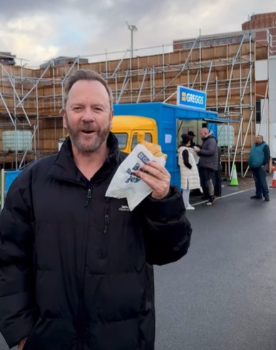 Kiefer Sutherland holding a pastry in front of a food truck.