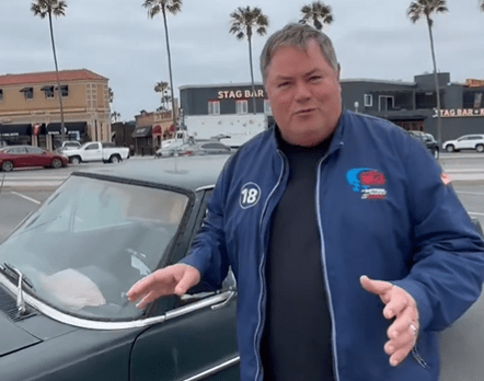 Mike Brewer standing by a vintage car.