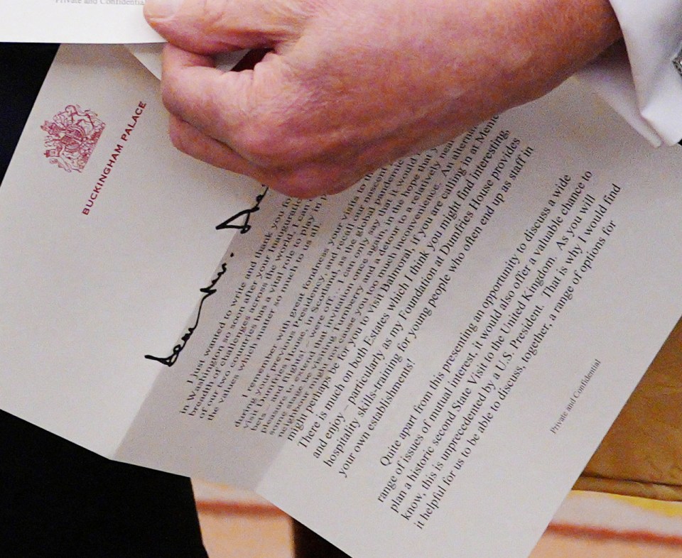 Hand holding a letter from Buckingham Palace.