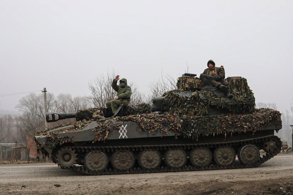 Russian servicemen on a camouflaged self-propelled gun.