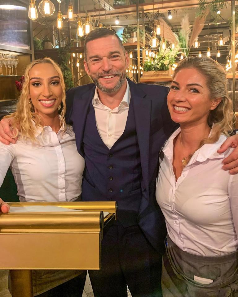 A man standing between two women, smiling for a photo.