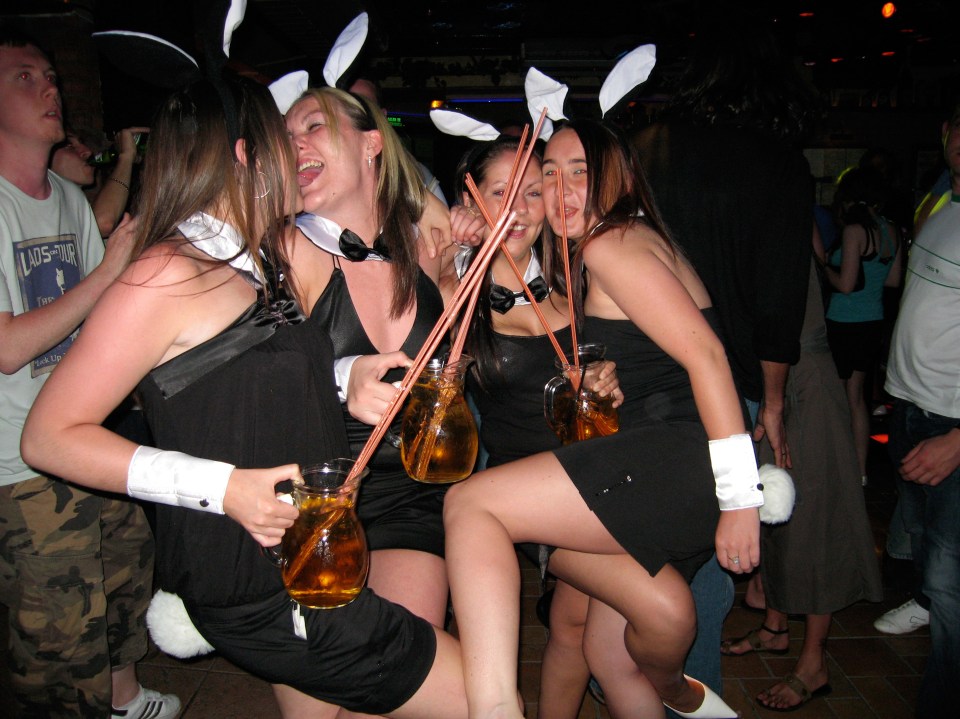 Four women in bunny costumes drinking from large pitchers.