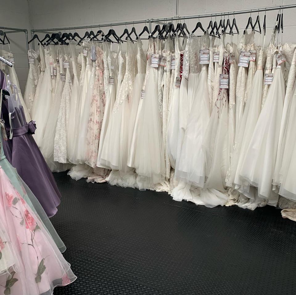 Many wedding dresses hanging on racks.