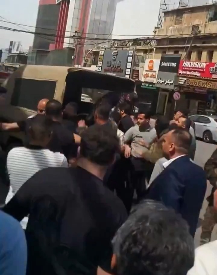 A crowd of people surrounding a vehicle in a city street.