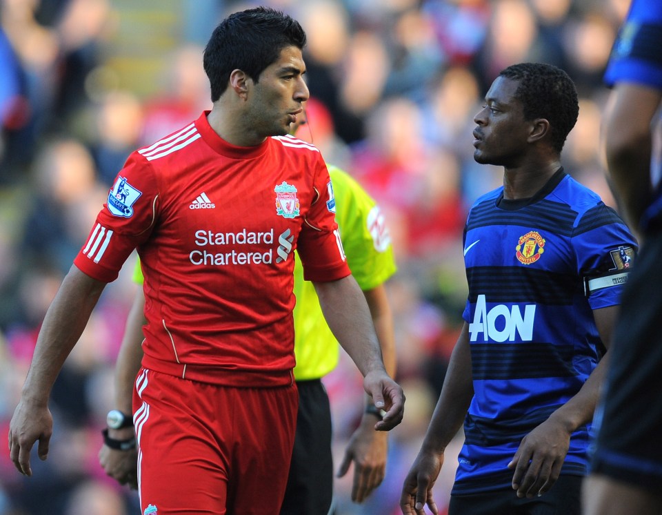 Luis Suárez and Patrice Evra facing each other on a soccer field.