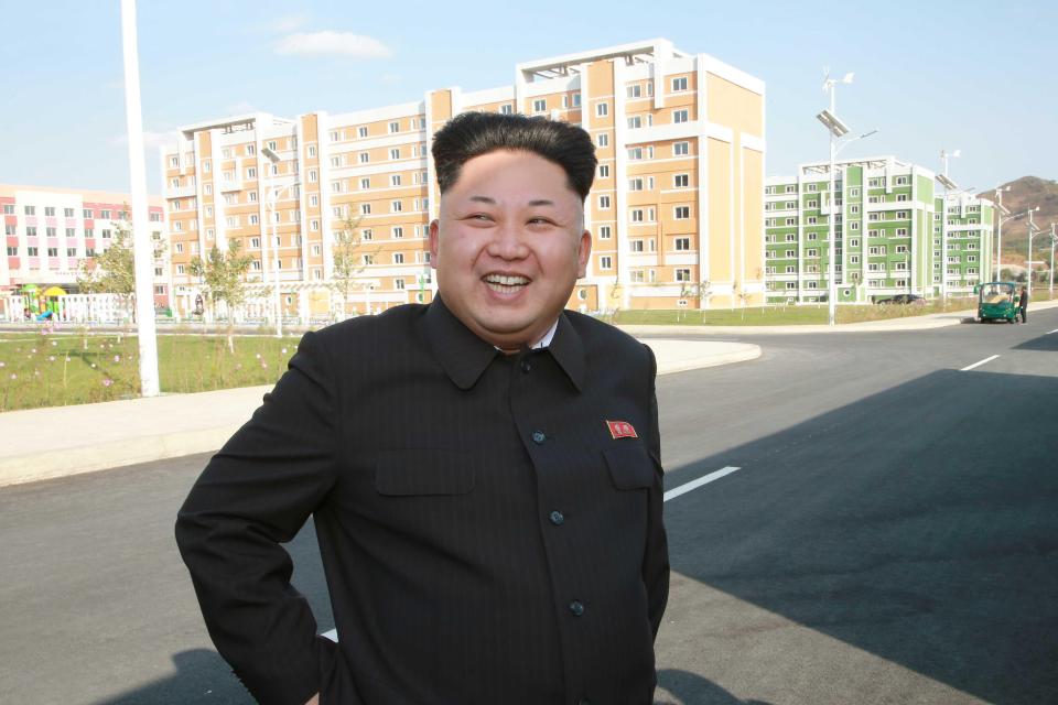 Kim Jong Un smiling in front of new apartment buildings.