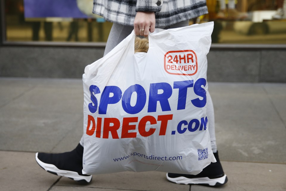 Person carrying a Sports Direct shopping bag.