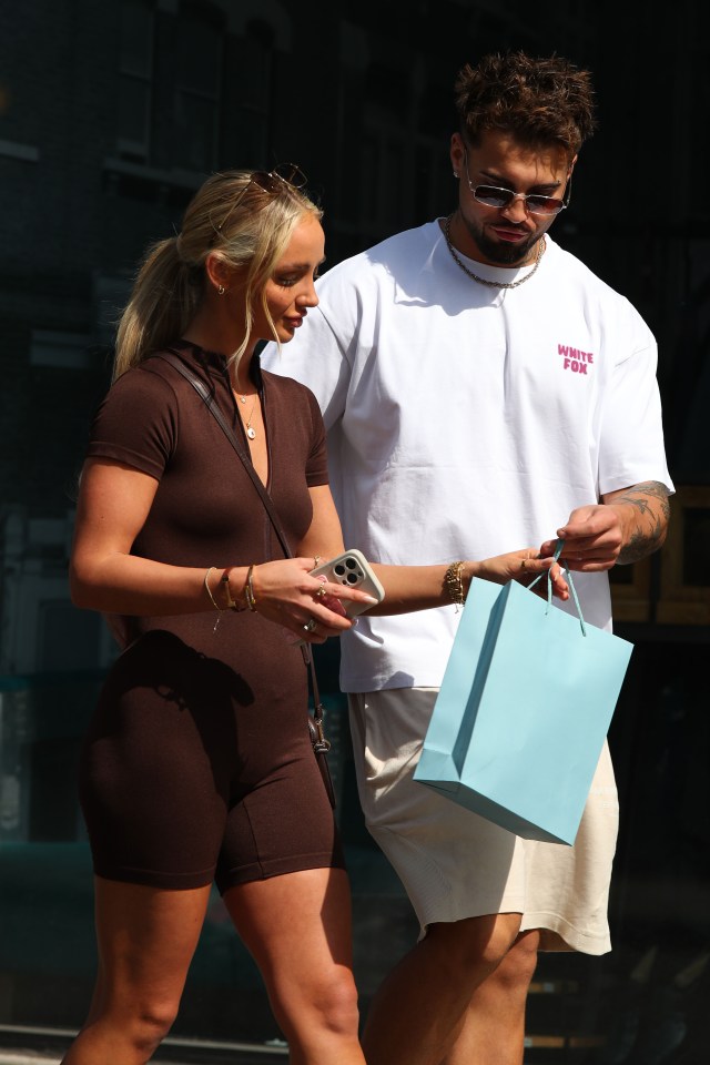 Nathan Campbell and Abi Moores leaving a baby boutique with a shopping bag.