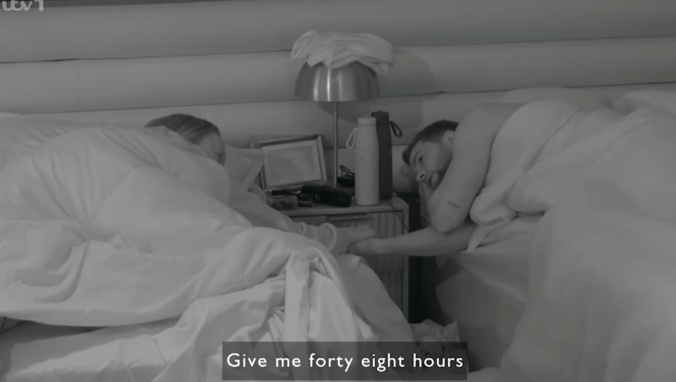 Screenshot of a couple lying in bed.