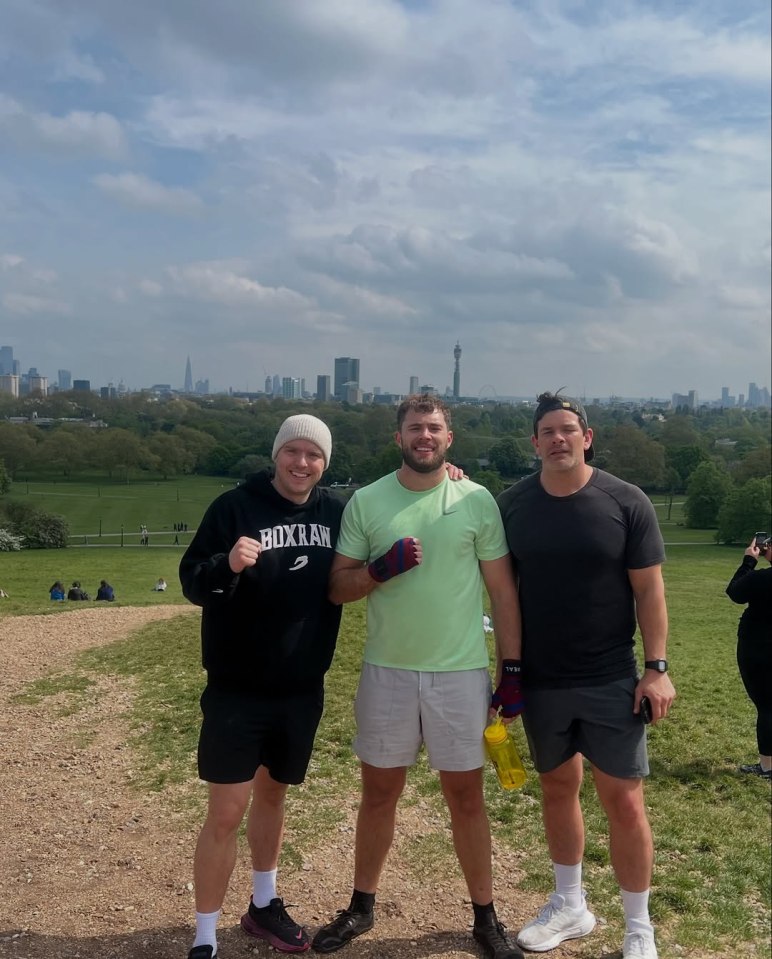 Three men posing on a hill overlooking London.