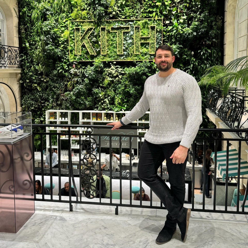 Man standing in front of a KITH logo on a green wall.