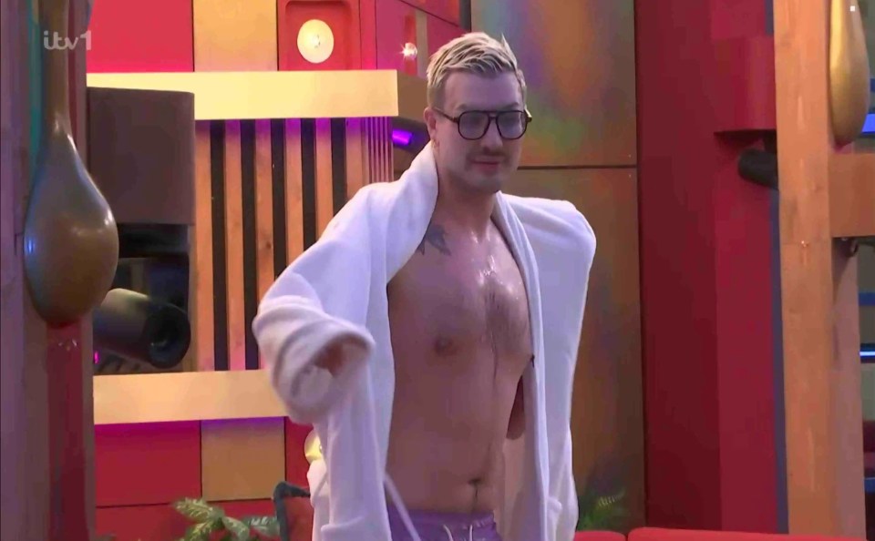A man in a white bathrobe and glasses partially removes his robe.
