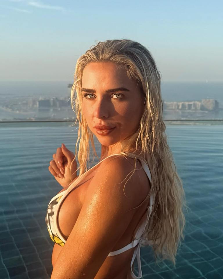 Woman in bikini by infinity pool overlooking city.