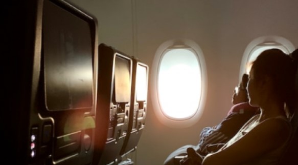Economy class airplane seats with passengers looking out the window.