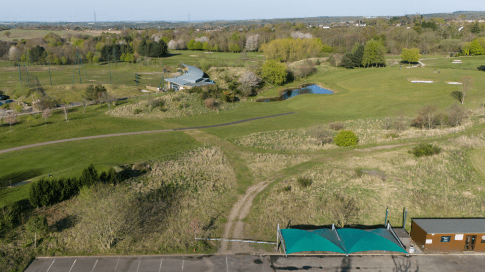 Aerial view of a golf course with clubhouse and driving range.