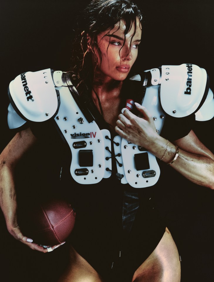 Woman in football shoulder pads holding a football.