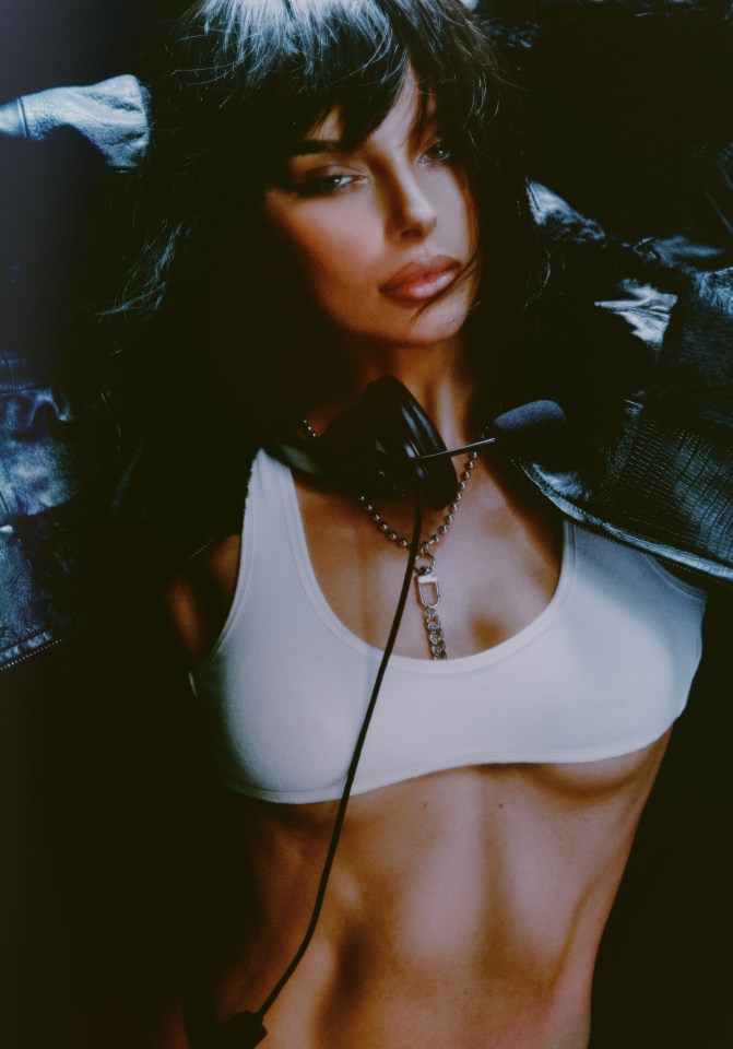 Portrait of Maura Higgins wearing a white sports bra and leather jacket.