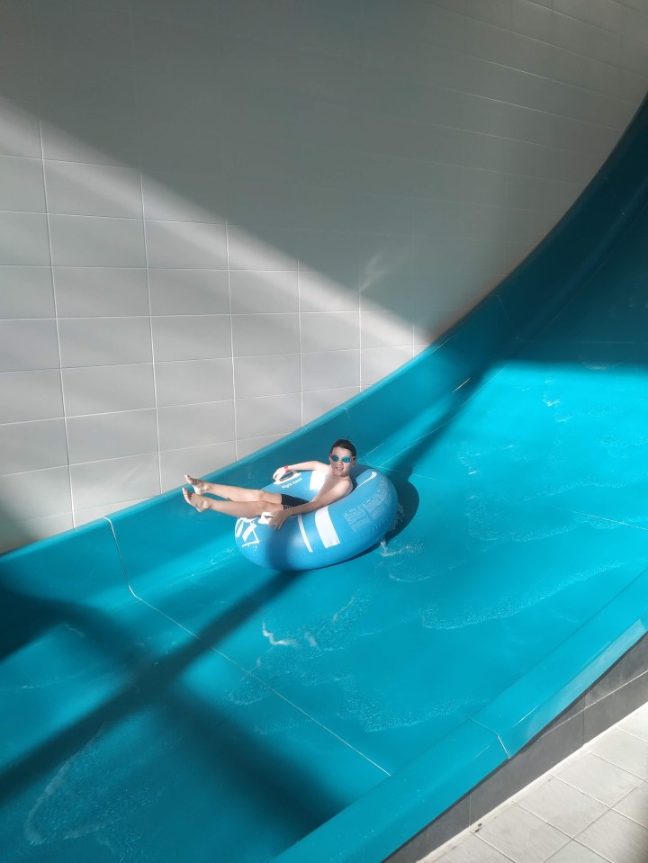 Boy on water slide in inner tube.