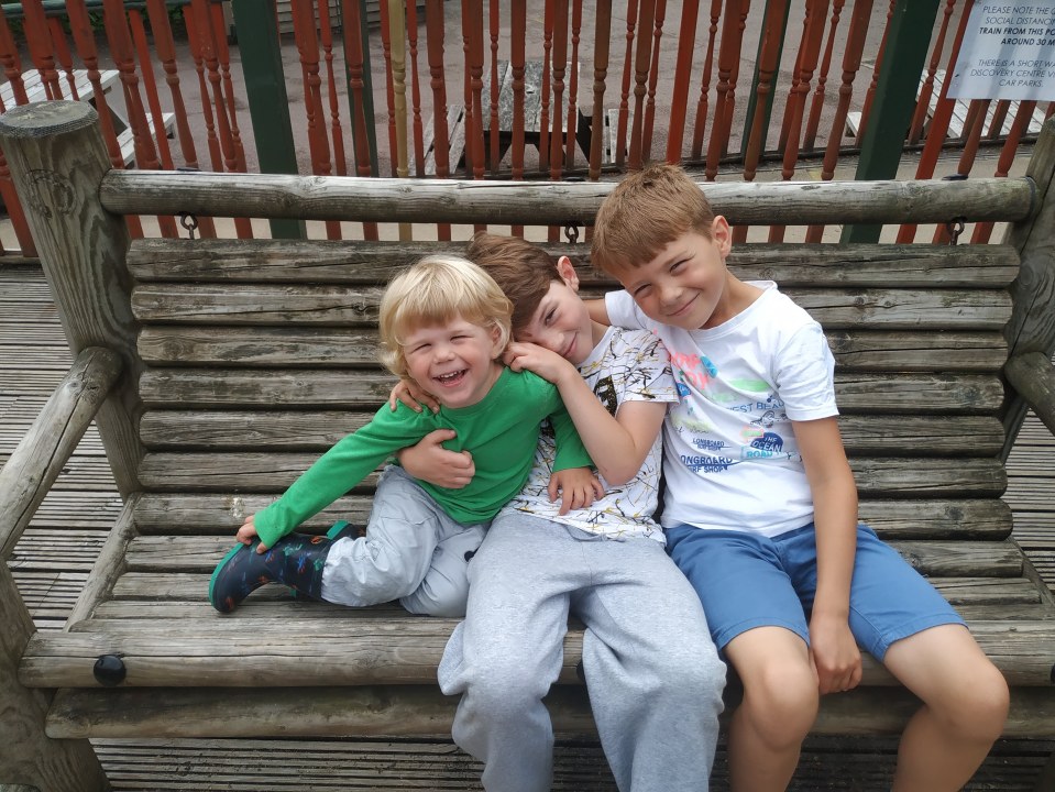 Three brothers hugging on a wooden bench.