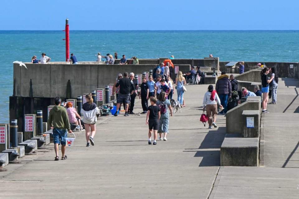 Holidaymakers enjoying a sunny day on a pier.