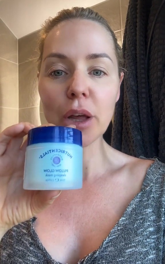 Woman holding jar of Nutrientials Pillow Glow sleeping mask.