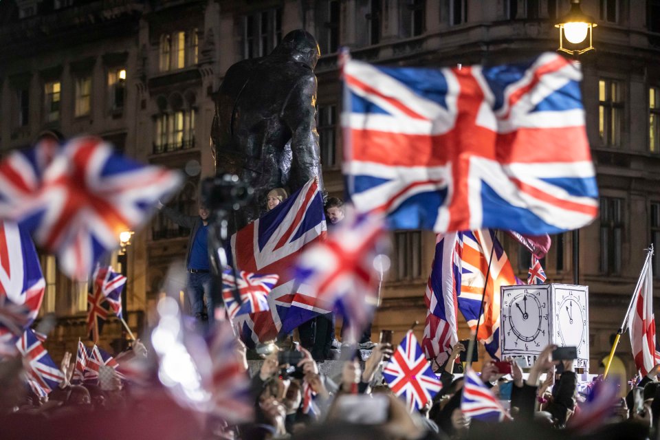 Pro-Brexit supporters celebrating in Parliament Square with Union Jack flags.