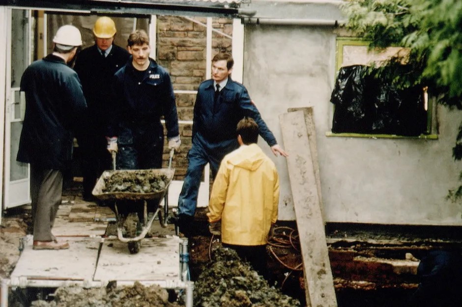 Police officers searching for human remains in a garden.