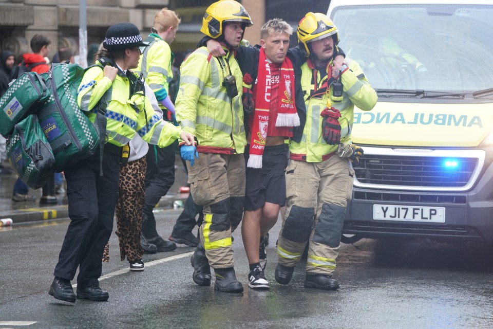 Police and emergency personnel assisting an injured man at a road traffic collision.