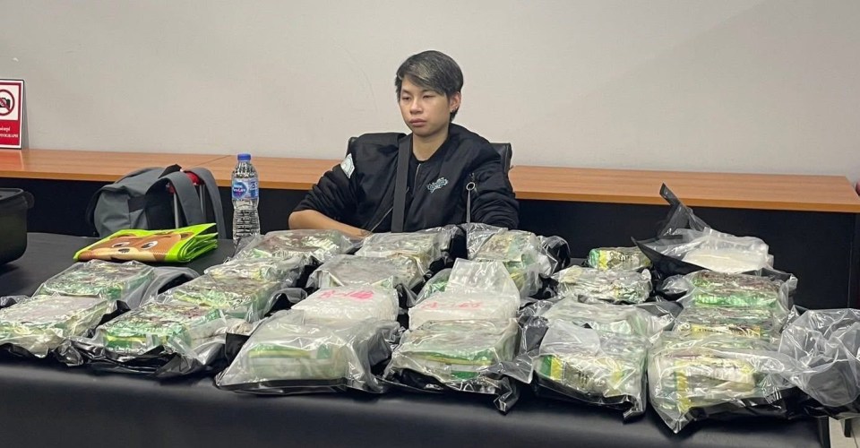A suspect sits at a table with numerous packages of confiscated methamphetamine.