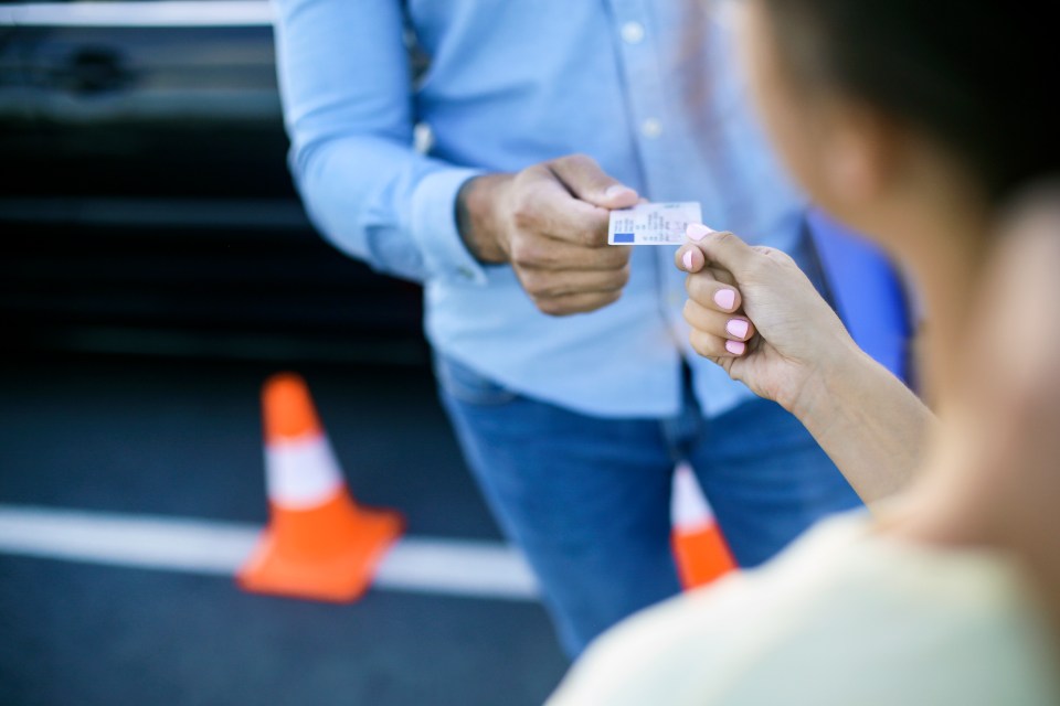 Driving instructor handing a young woman her driver's license.