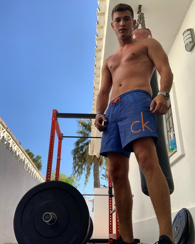Man in blue shorts standing in front of weightlifting equipment.